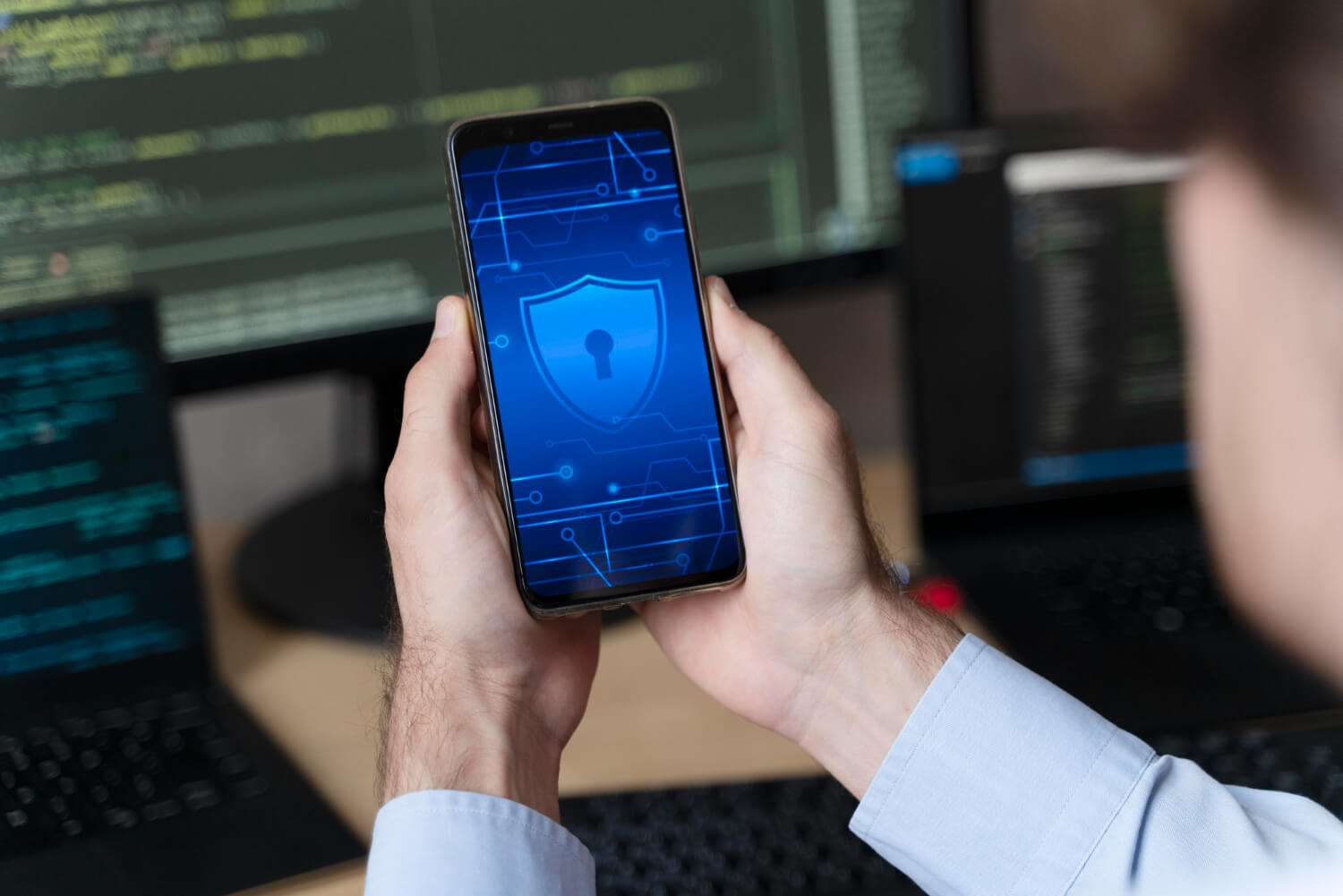 Person holding phone with cybersecurity icon displayed.